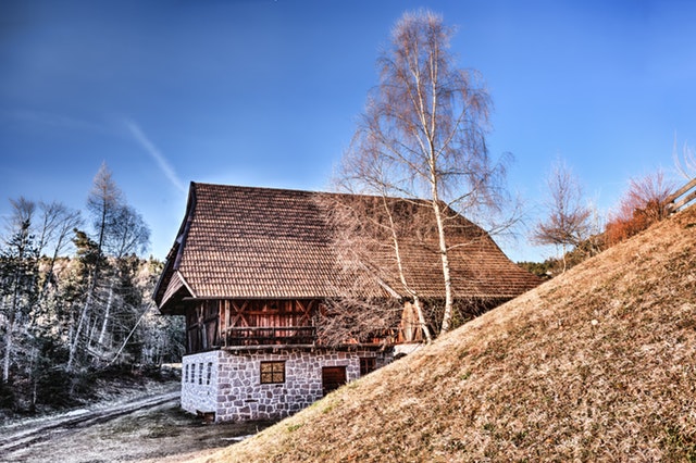 Drevená chata na murovaných vysokých základoch a zasnežená krajina